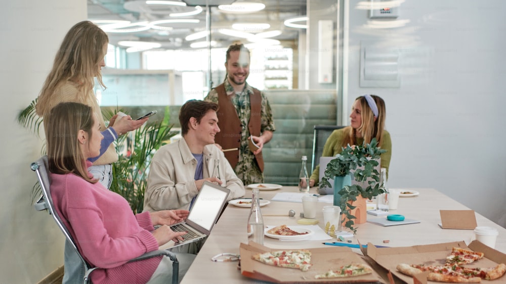 a group of people sitting around a table eating pizza