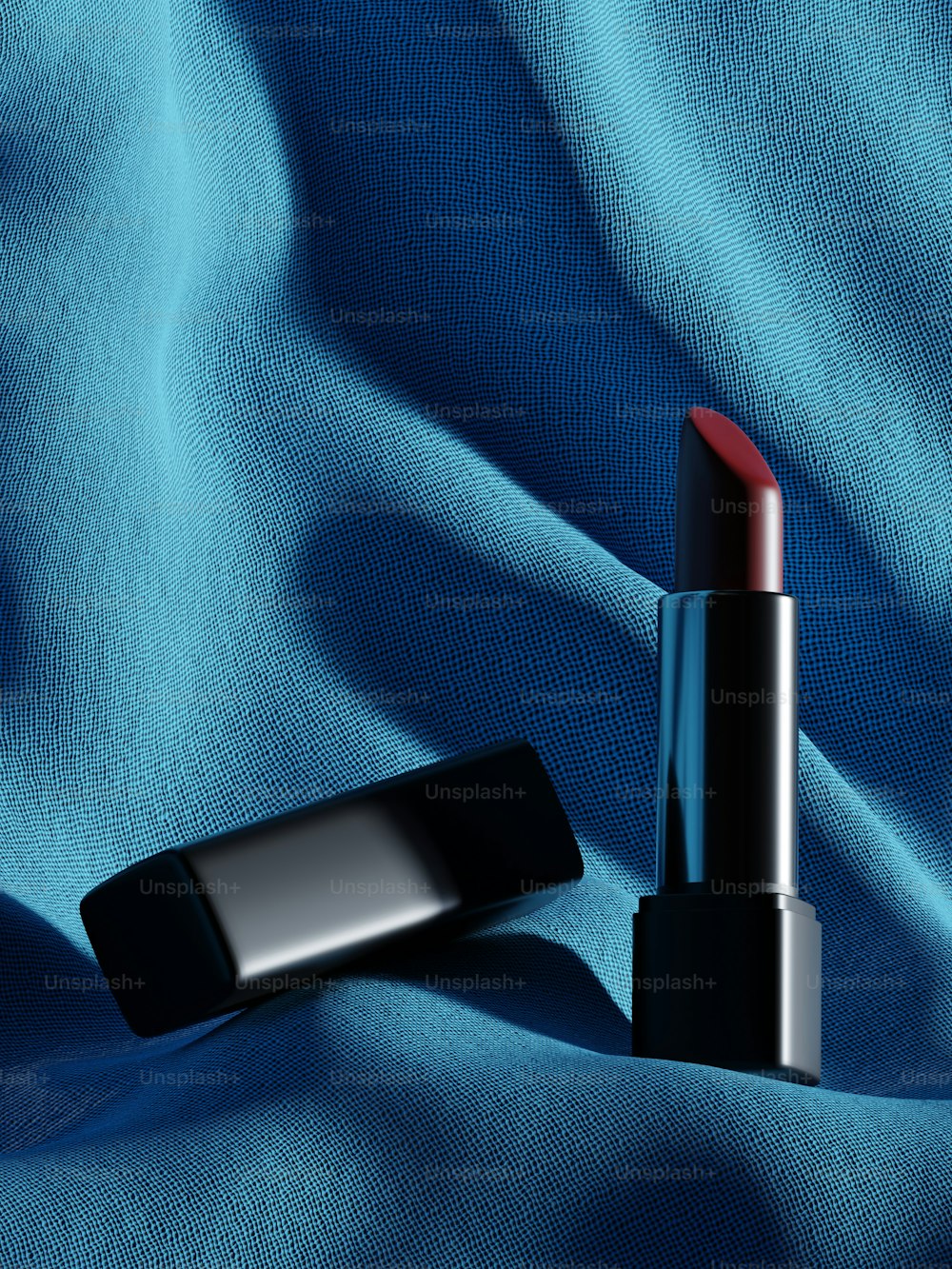 a red lipstick sitting on top of a blue cloth