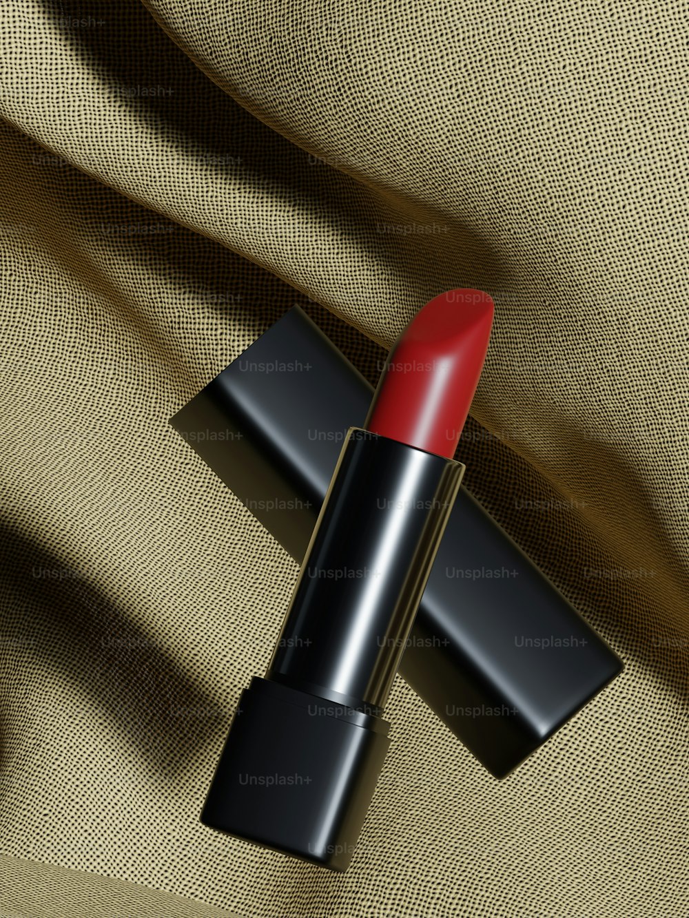 Un lápiz labial rojo sentado encima de una tela beige