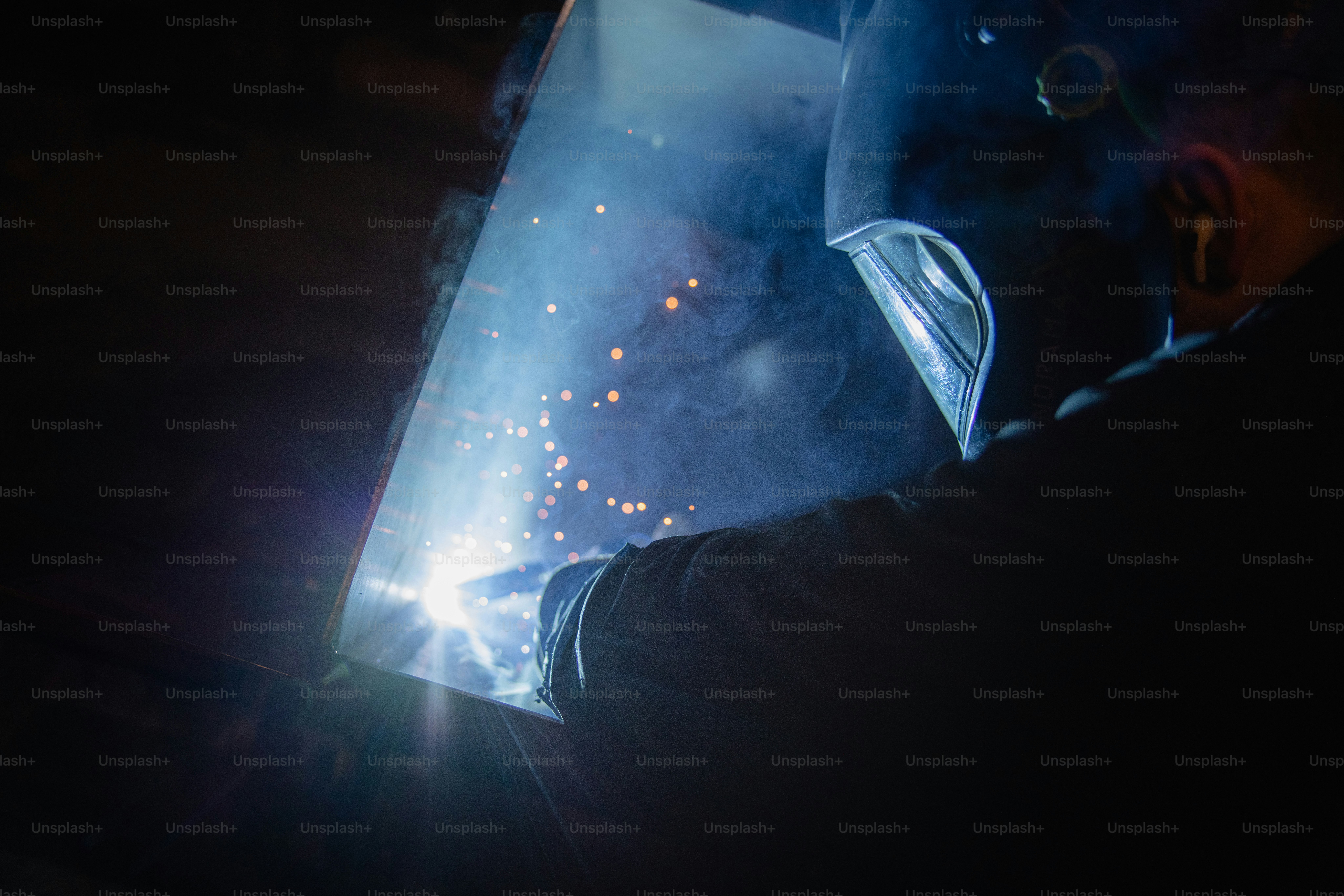 Schweißer bei der Bearbeitung eines Metallstücks im Dunkeln