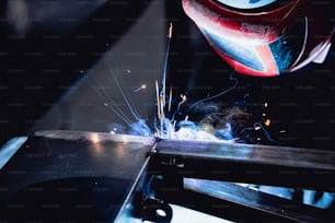un saldatore che taglia un pezzo di metallo con una smerigliatrice