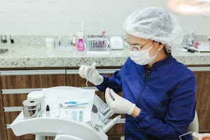 a woman in a dentist's office wearing a mask and gloves