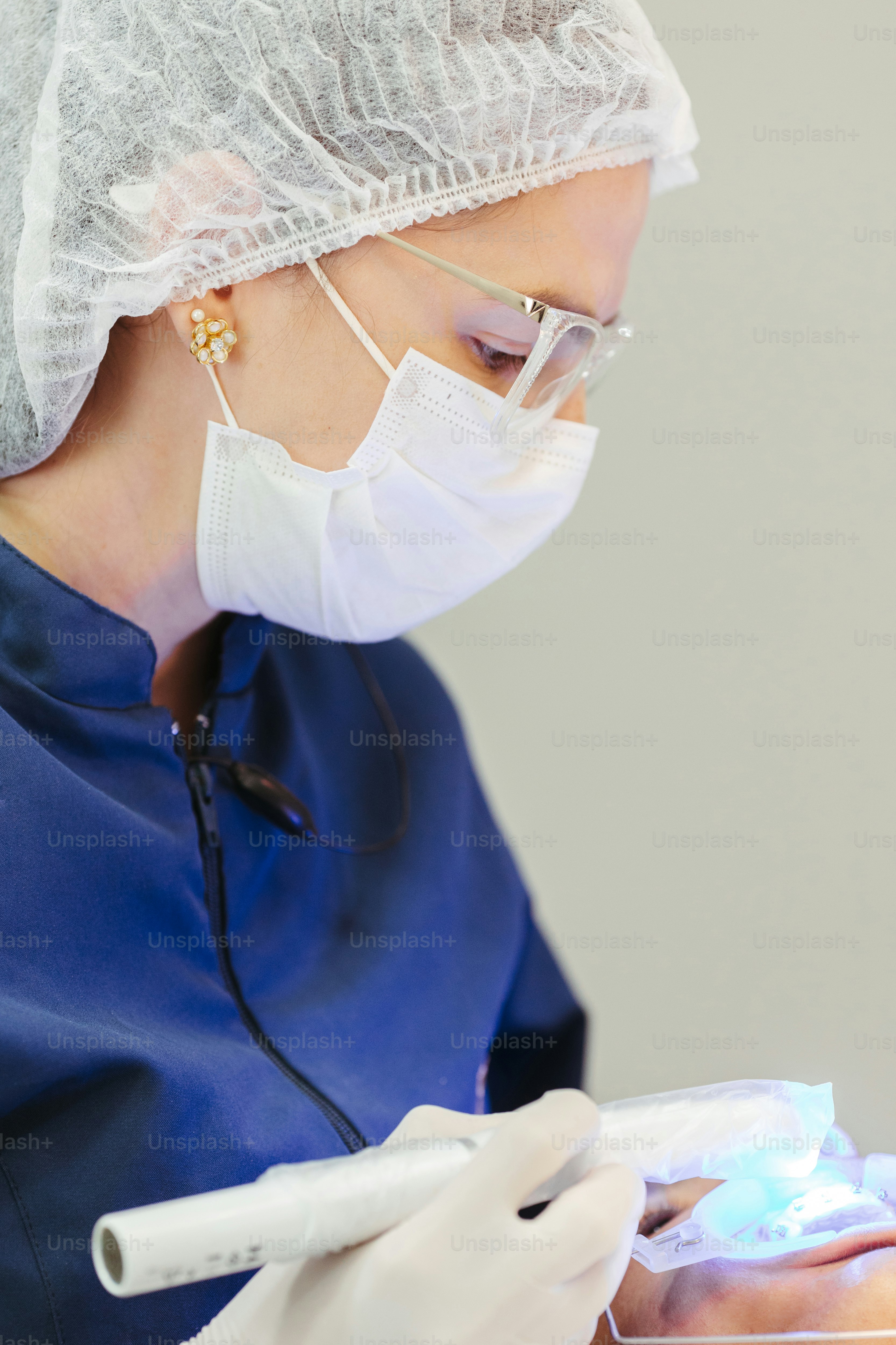 a woman in a surgical gown and mask holding a toothbrush