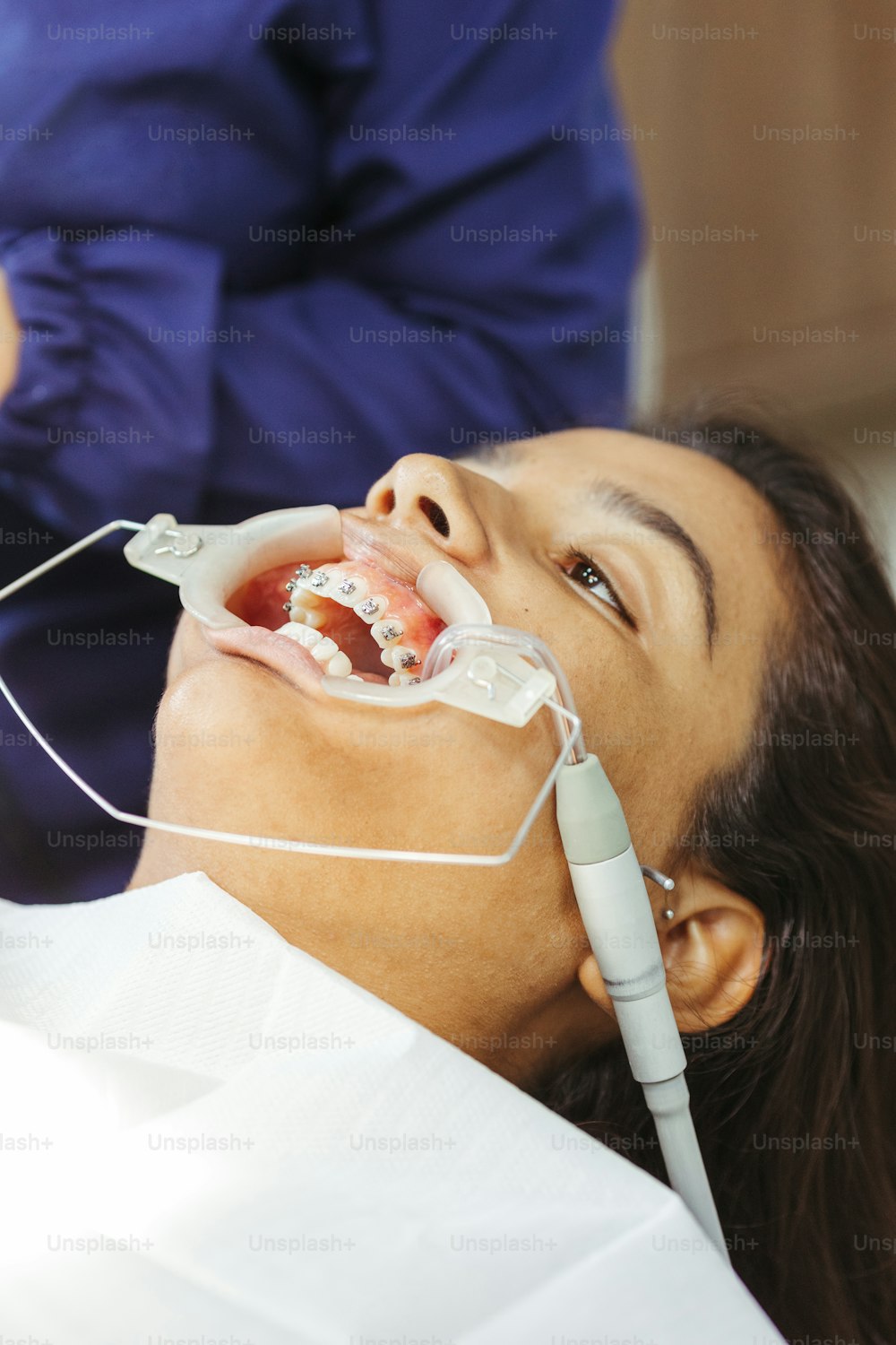 uma mulher na cadeira de um dentista que verifica os dentes