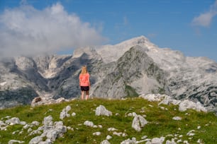 a woman standing on top of a lush green hillside