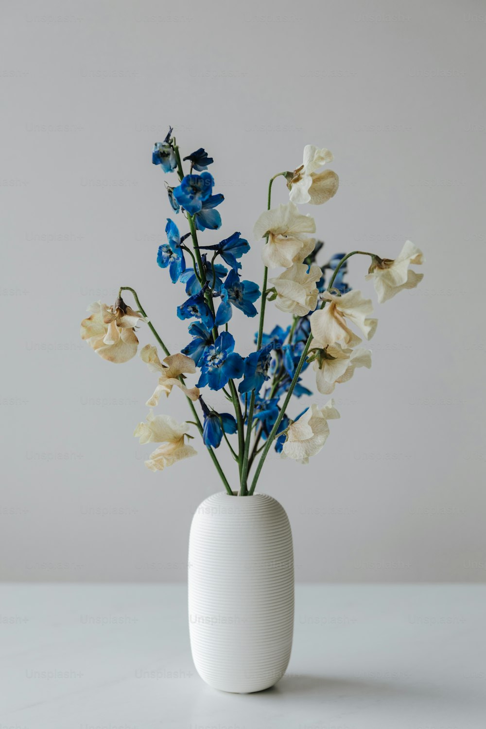 a white vase filled with blue and white flowers
