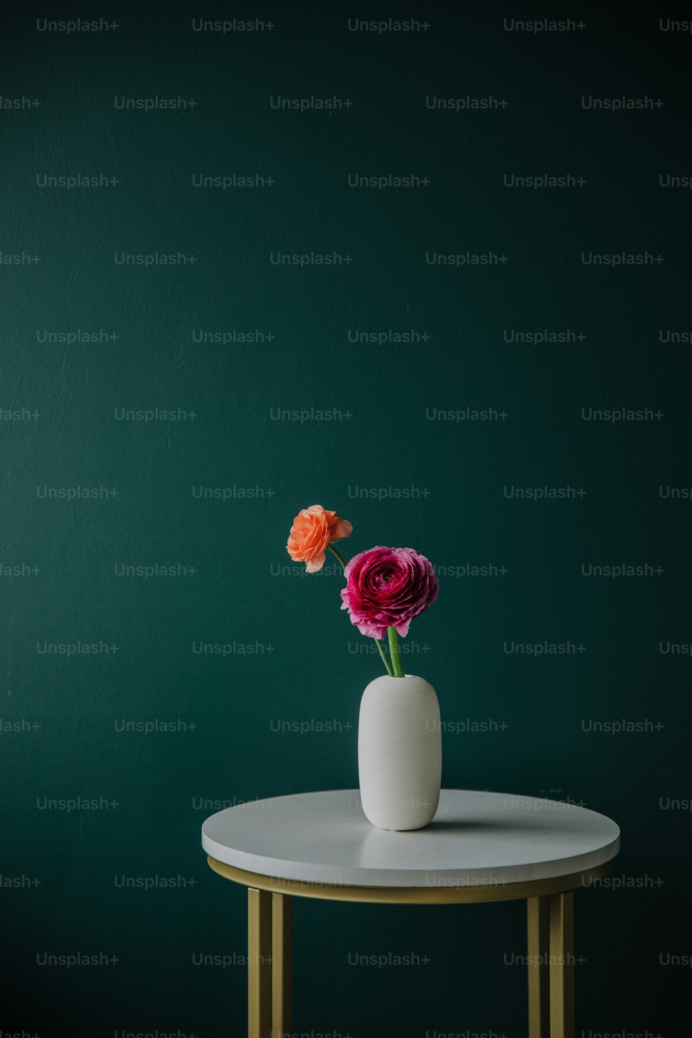a white table with two flowers in a vase