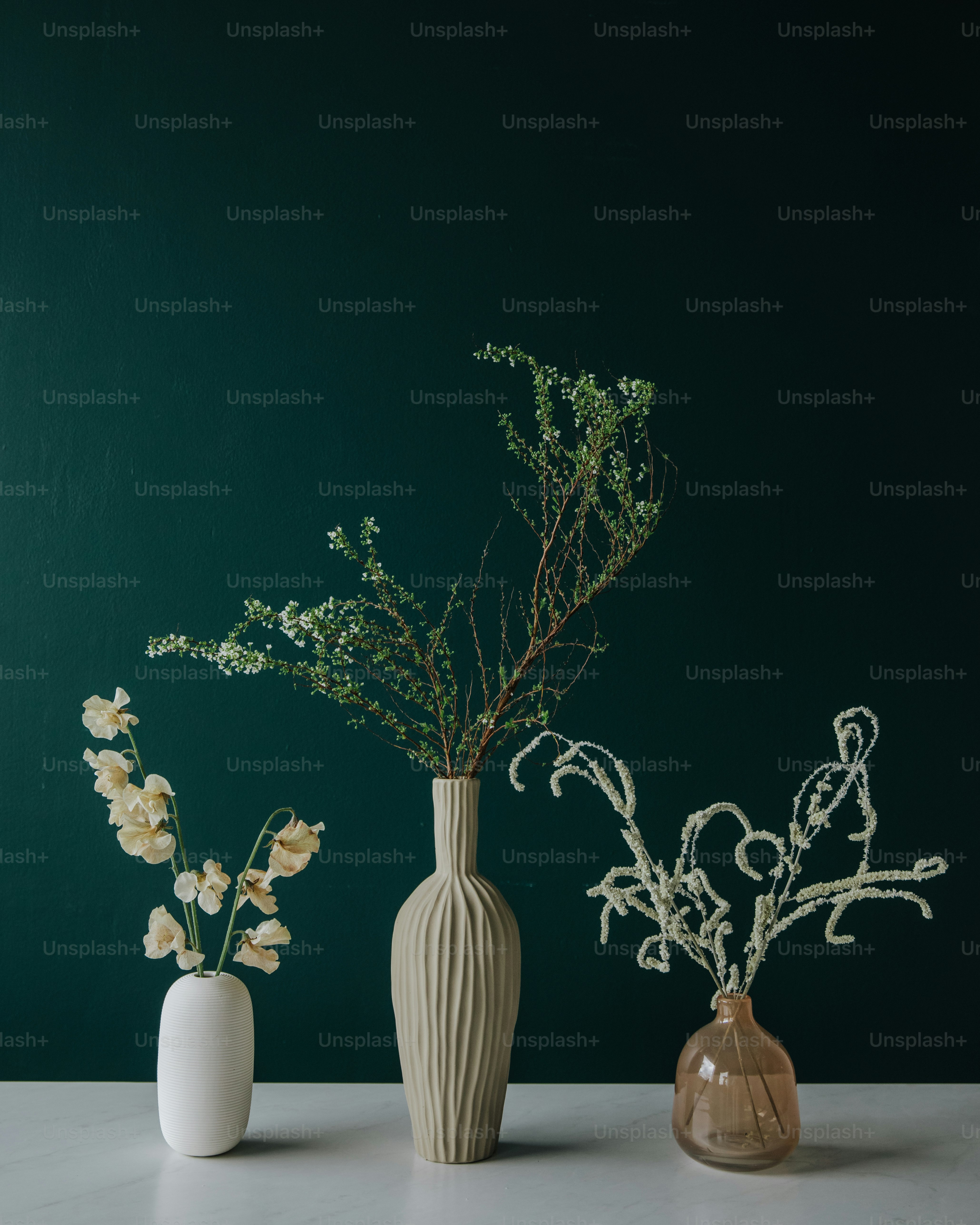 three vases with flowers in them on a table