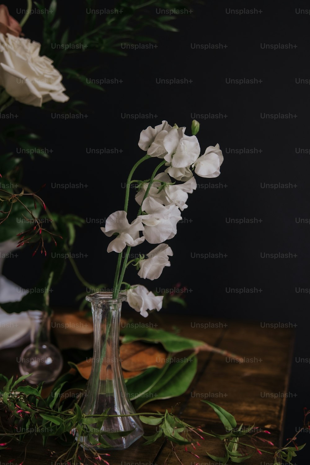 eine Vase gefüllt mit weißen Blumen auf einem Holztisch