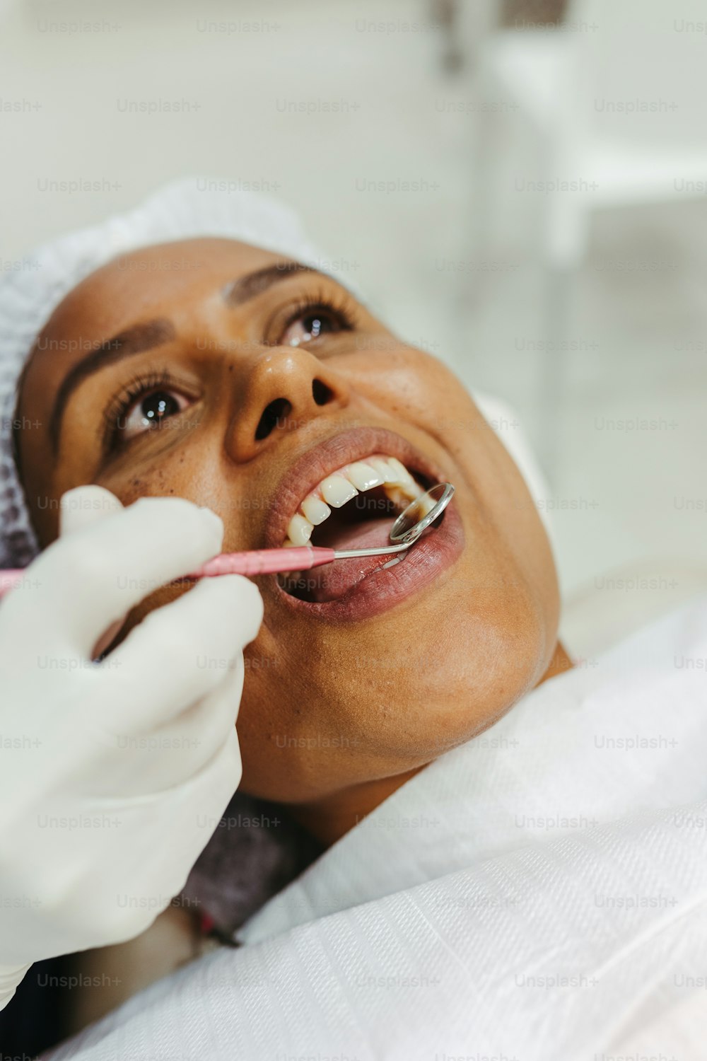 uma mulher na cadeira de um dentista com uma escova de dentes na boca