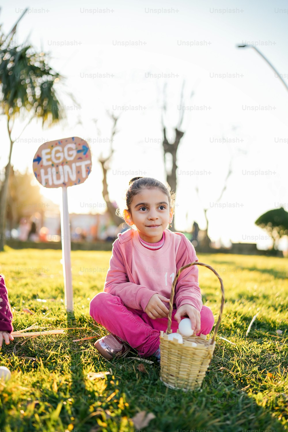 Ein kleines Mädchen sitzt im Gras mit einem Korb voller Eier