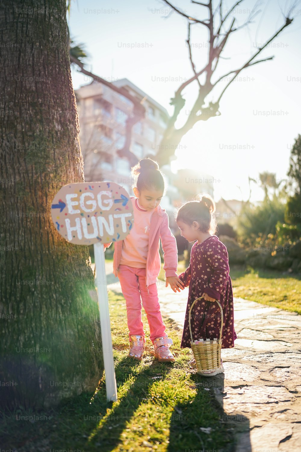 two little girls standing next to a tree
