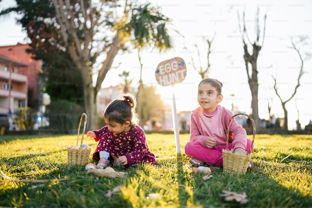 two little girls sitting in the grass with baskets