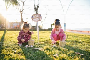 two little girls playing with eggs in the grass