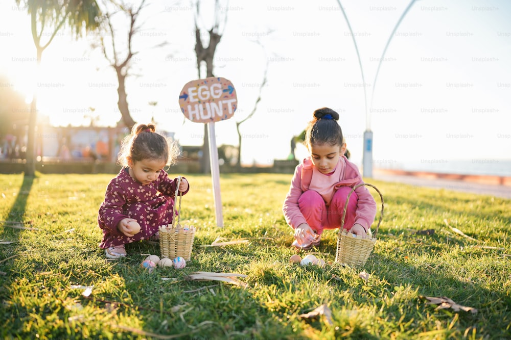two little girls playing with eggs in the grass