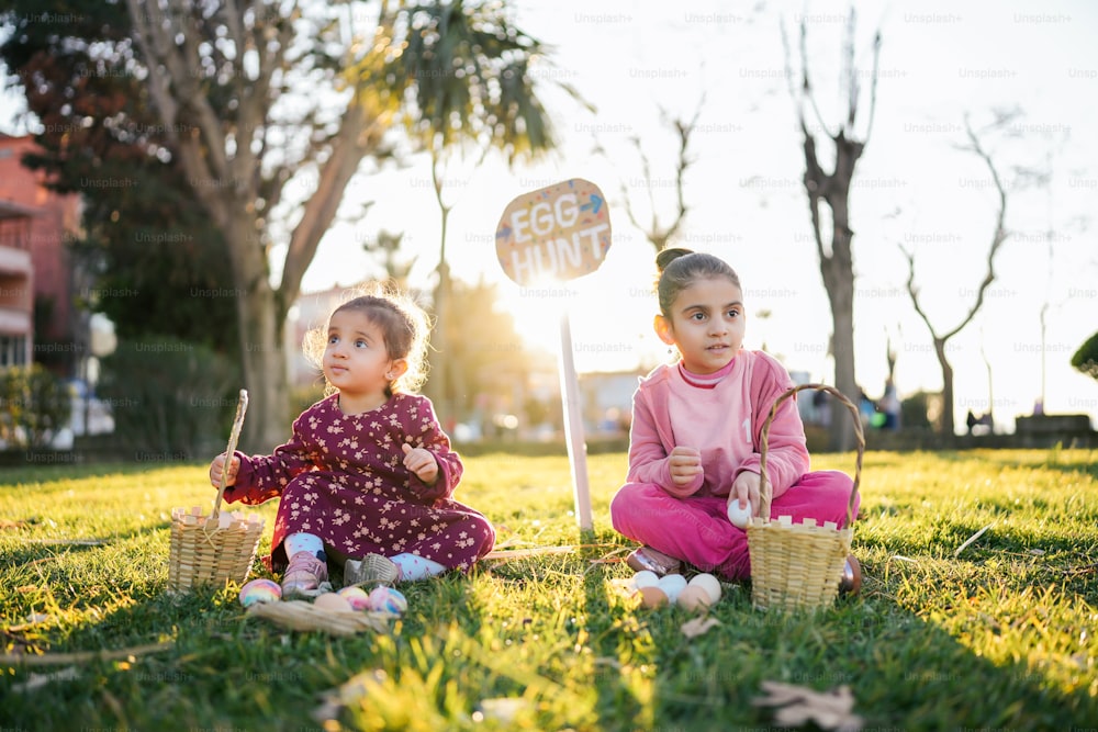 two little girls sitting in the grass with eggs