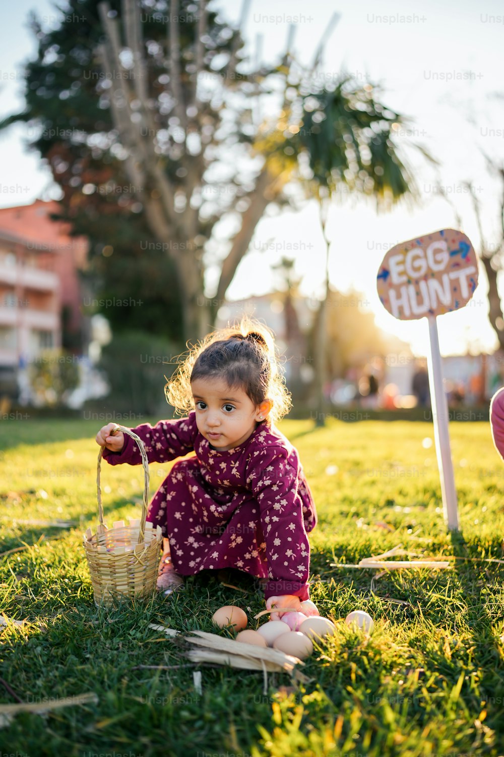 a little girl sitting in the grass with a basket