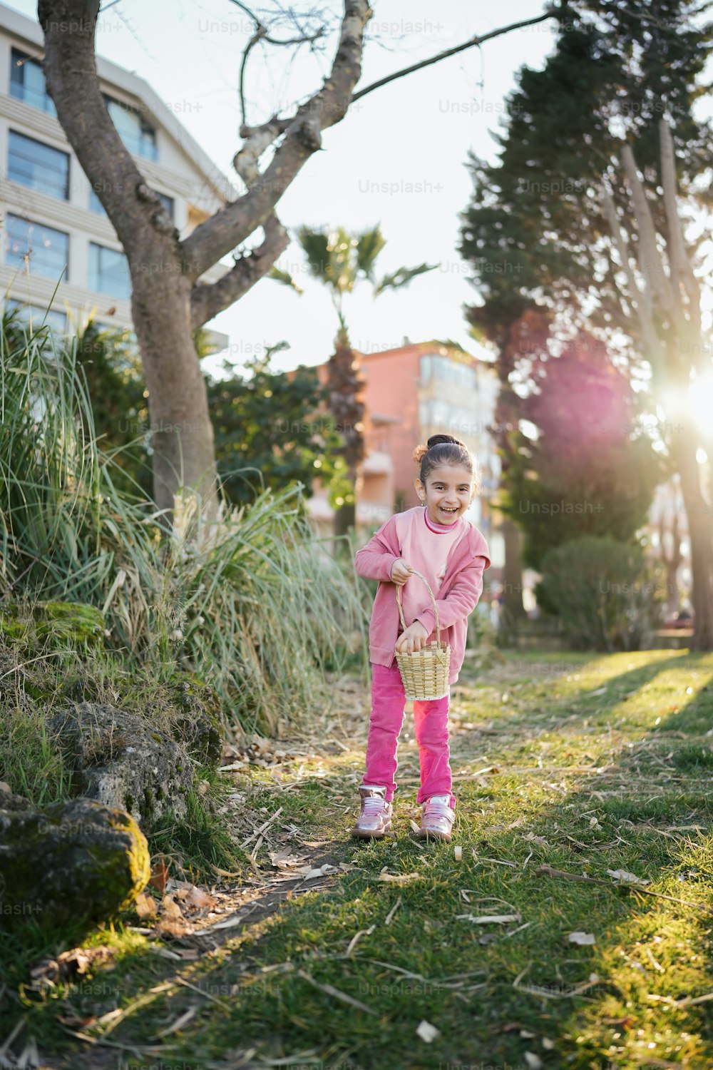 Ein kleines Mädchen steht im Gras und hält einen Korb in der Hand