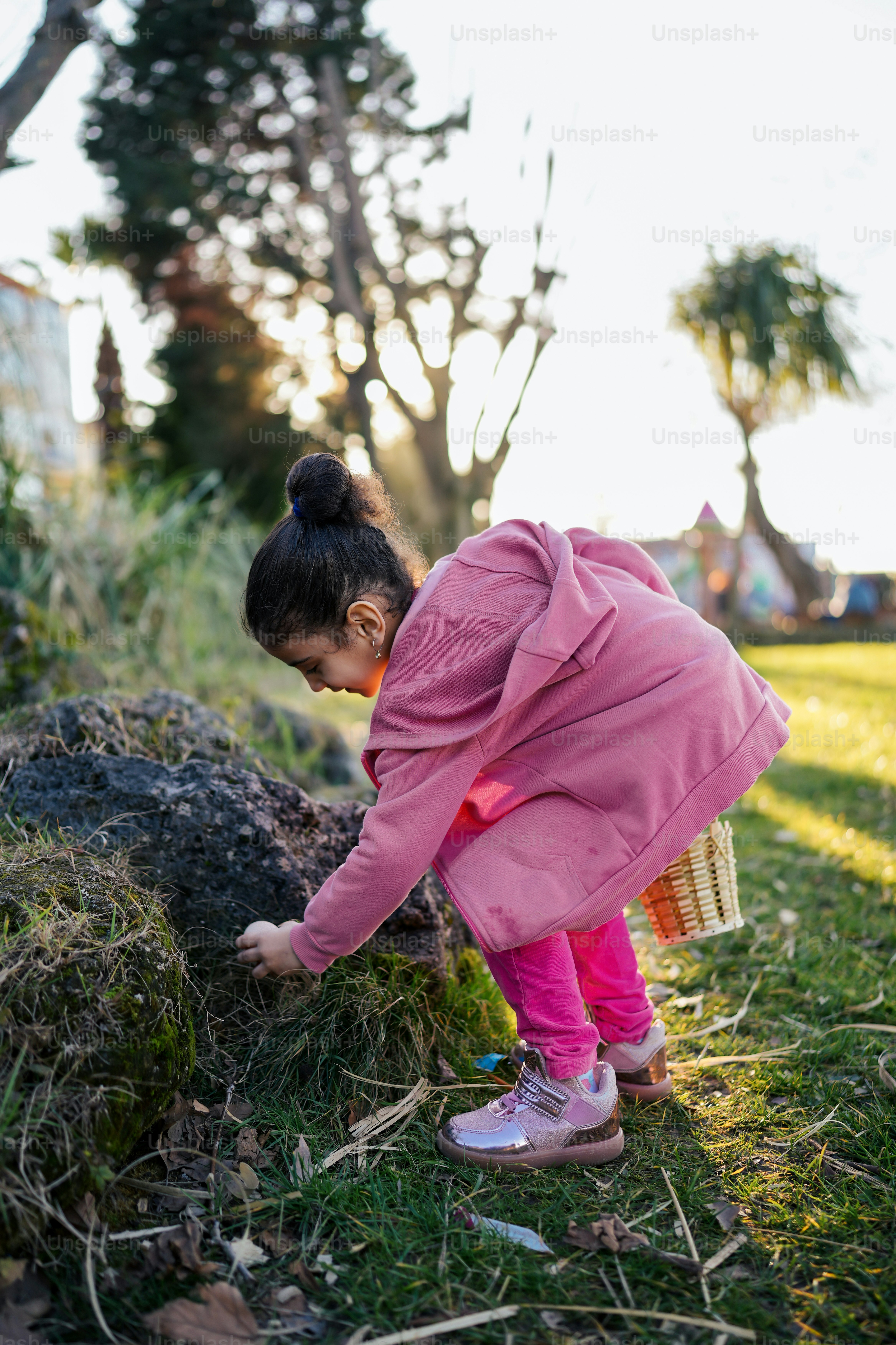 Una bambina in un cappotto rosa sta raccogliendo l'erba