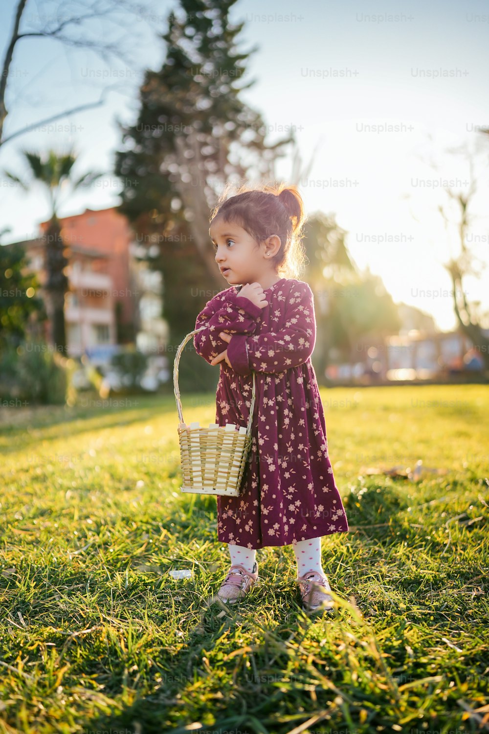 a little girl standing in the grass holding a basket