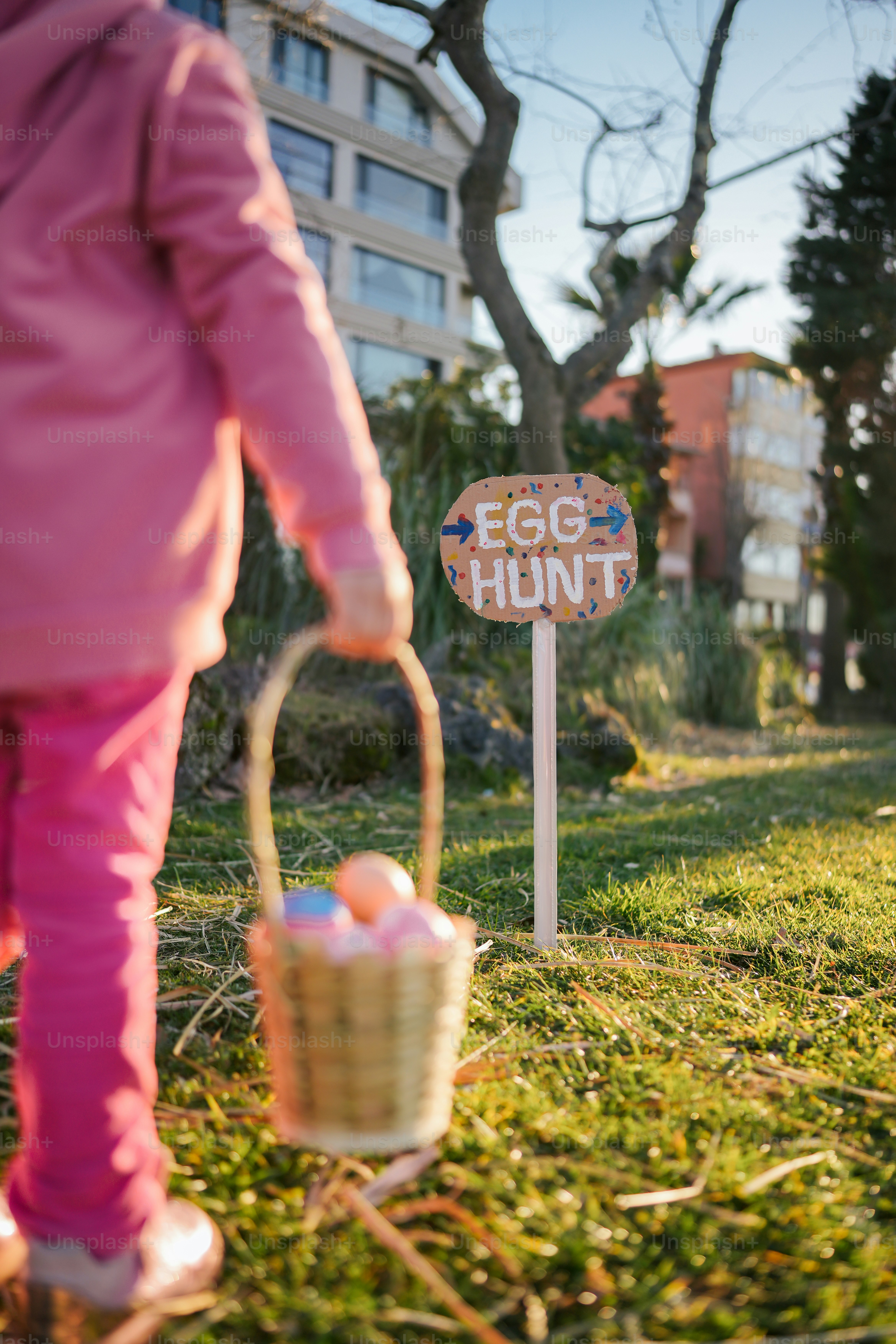 Une petite fille tenant un panier d’œufs devant un panneau de chasse aux œufs
