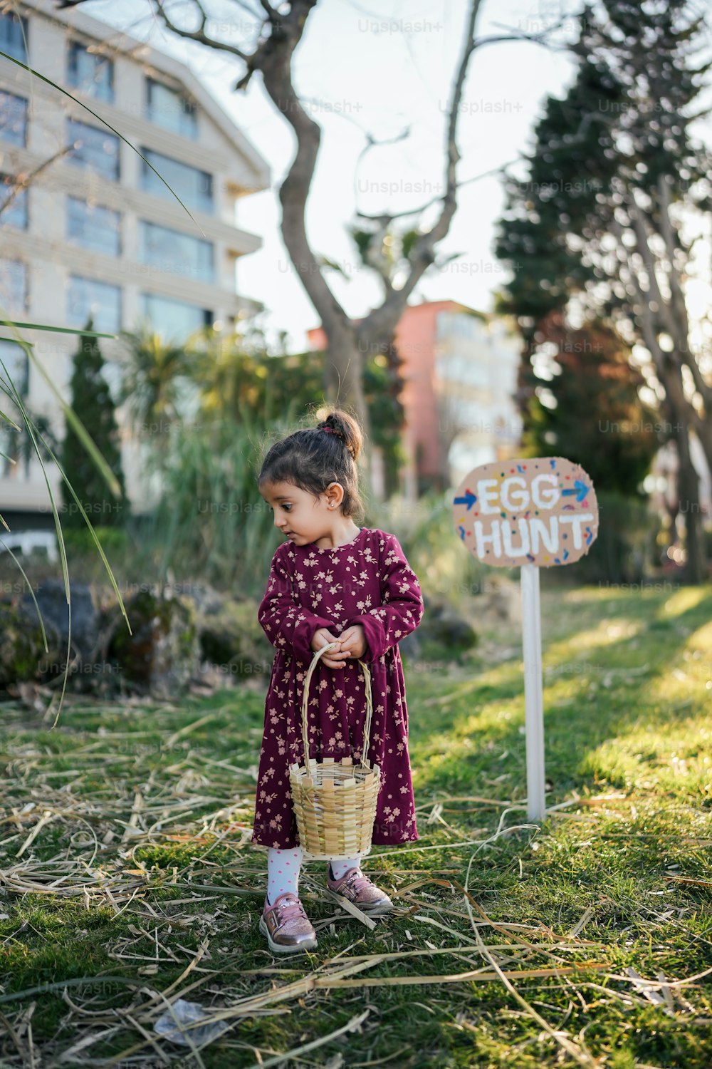 a little girl holding a basket standing next to a sign