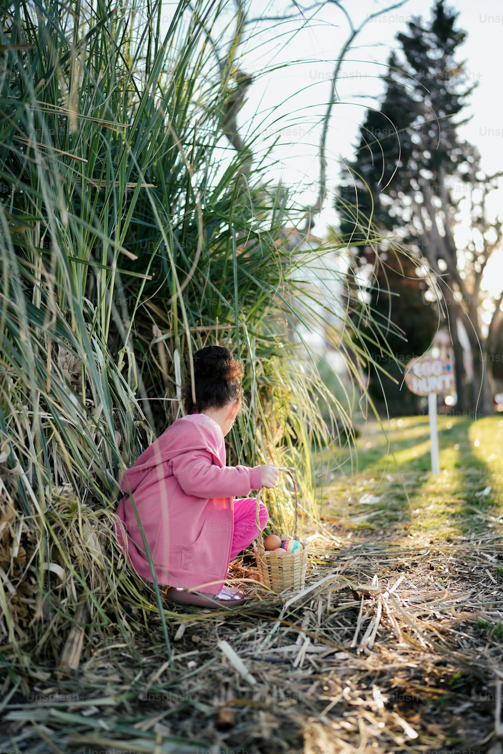 草むらに座っているピンクのジャケットを着た少女