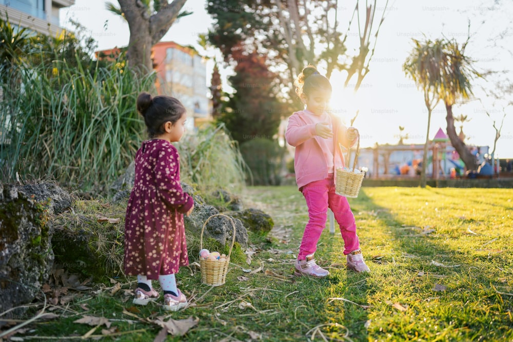 two little girls standing in the grass with baskets