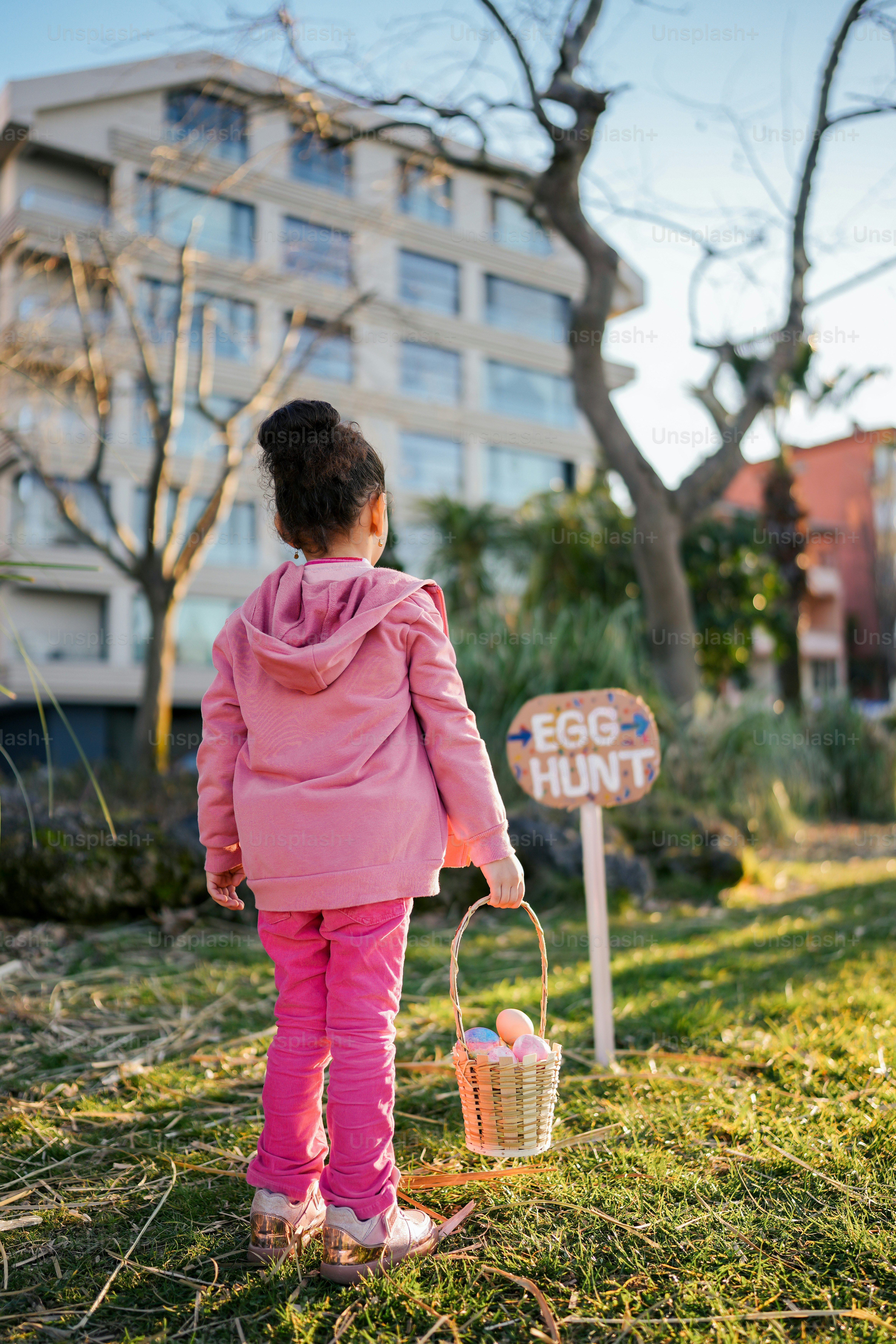 Una niña con una chaqueta rosa sosteniendo una canasta