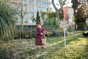 a little girl holding a basket standing next to a sign