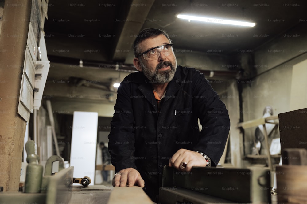 a man with a beard and glasses working on a piece of wood