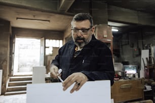 Un hombre con barba y gafas trabajando en un pedazo de papel
