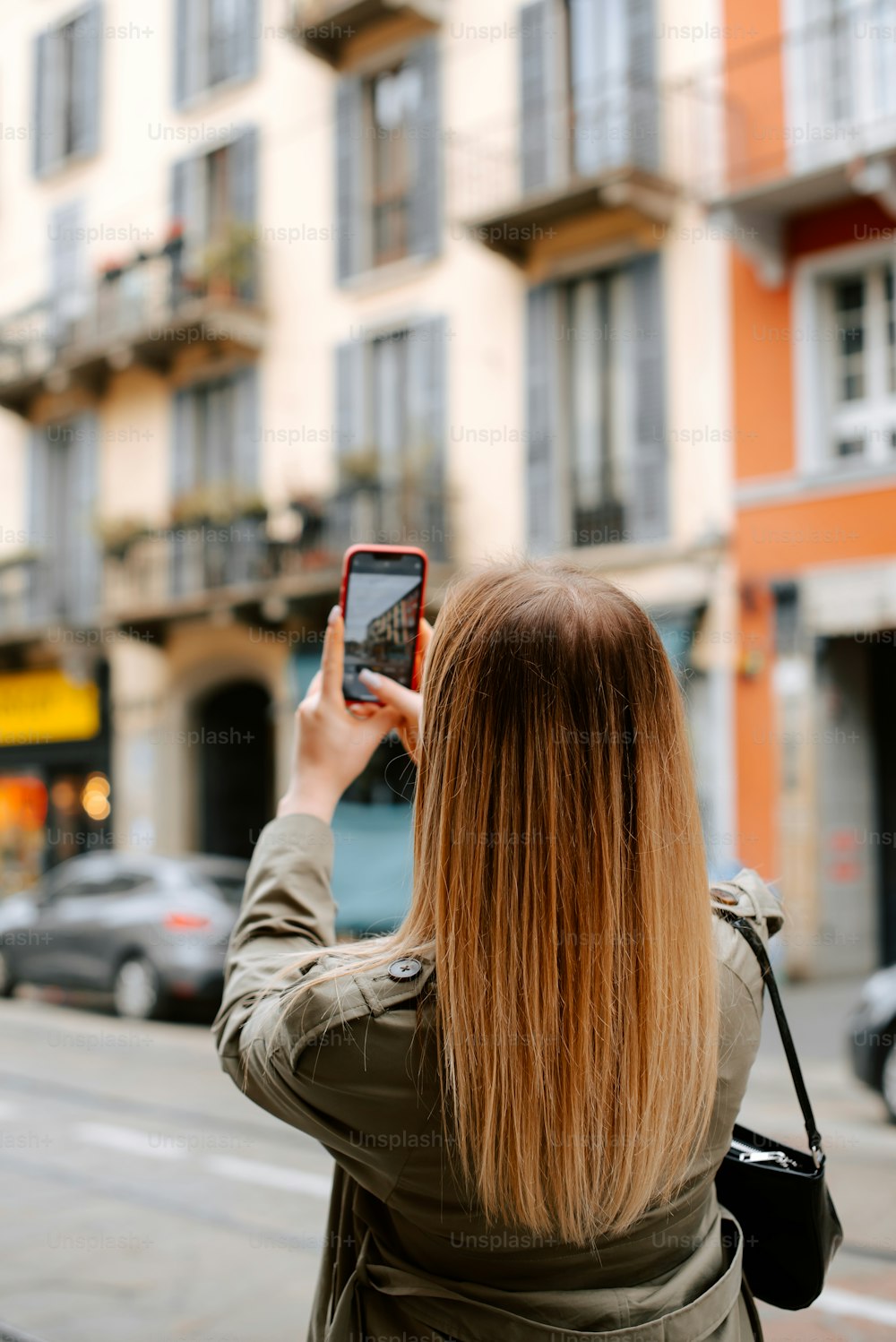 a woman taking a picture of a building with her cell phone