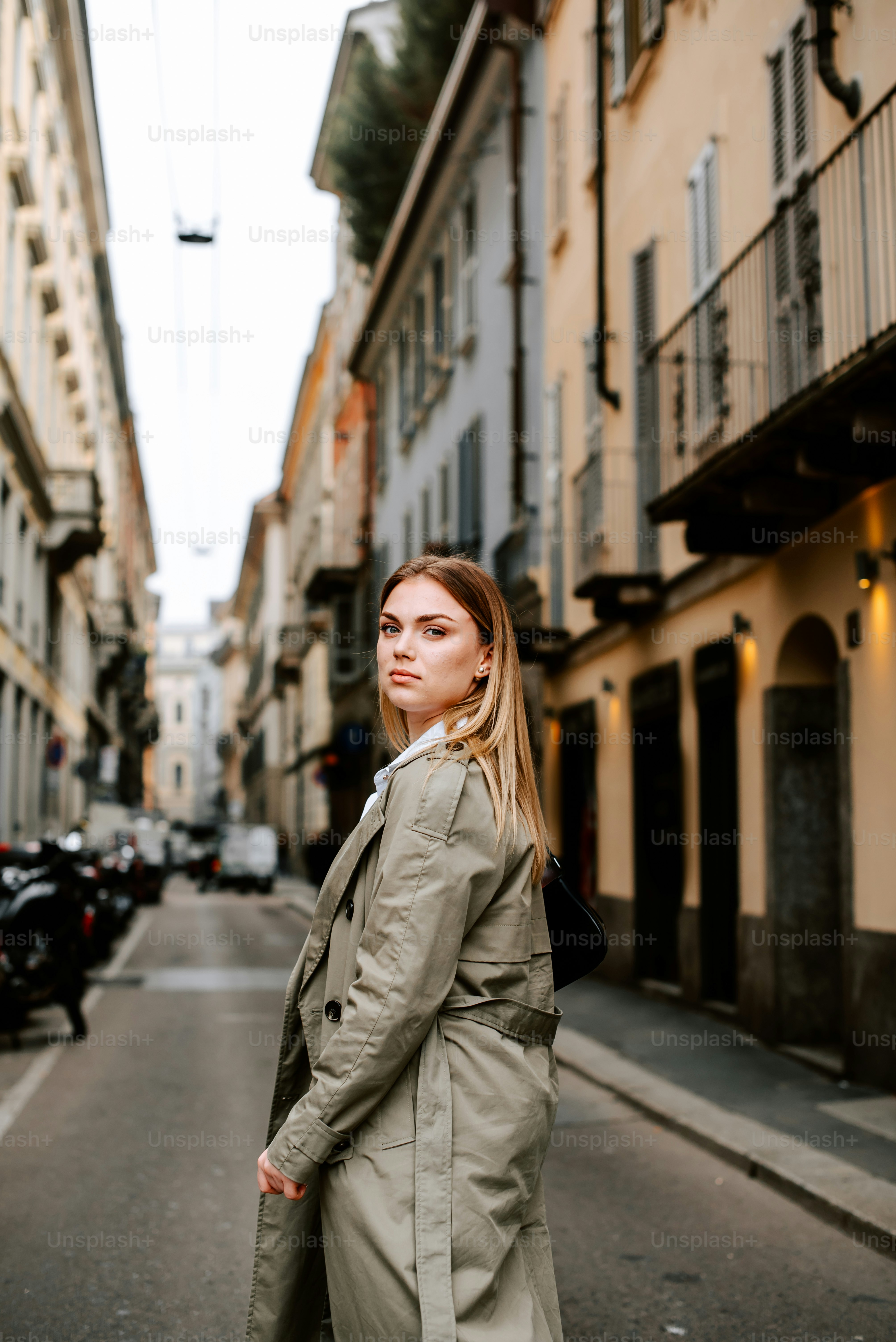 Une femme en trench-coat debout dans une rue