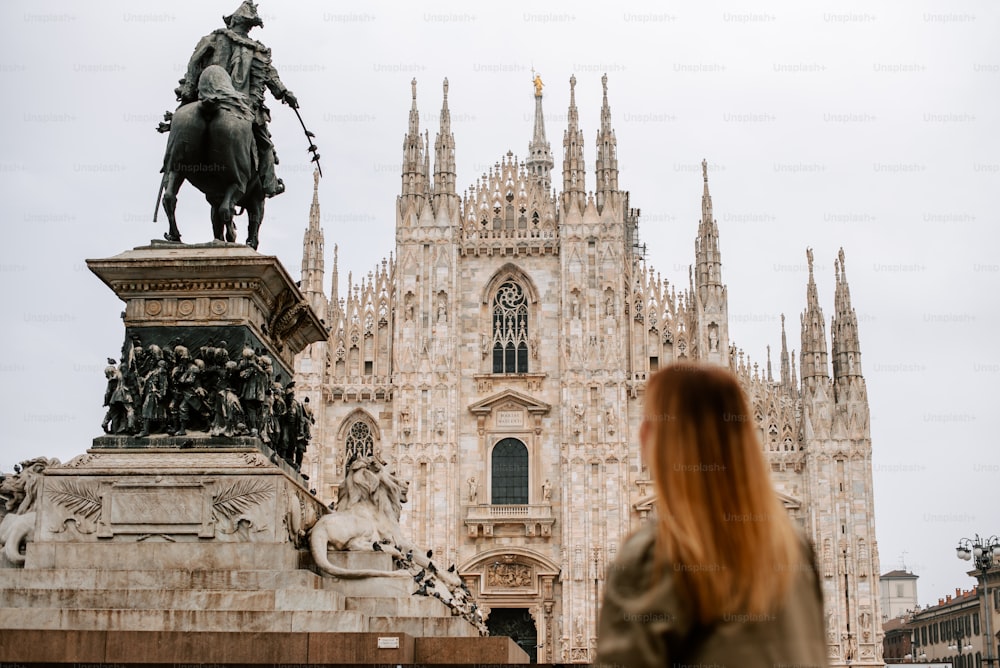 una donna che guarda una statua di un uomo su un cavallo di fronte a un