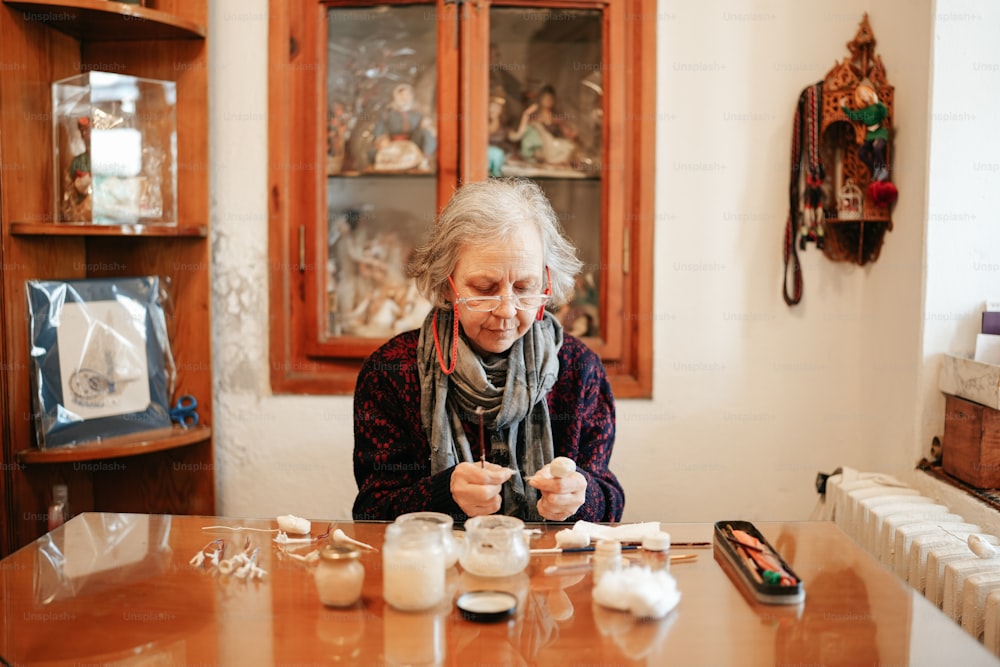 Eine ältere Frau sitzt an einem Tisch mit Kerzen vor sich