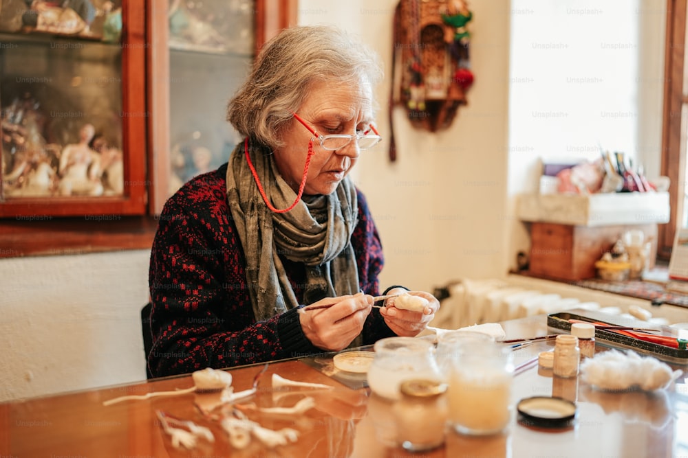 Eine Frau sitzt an einem Tisch und arbeitet an einem Kunstwerk
