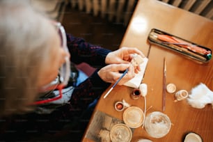 a woman sitting at a table working on crafts