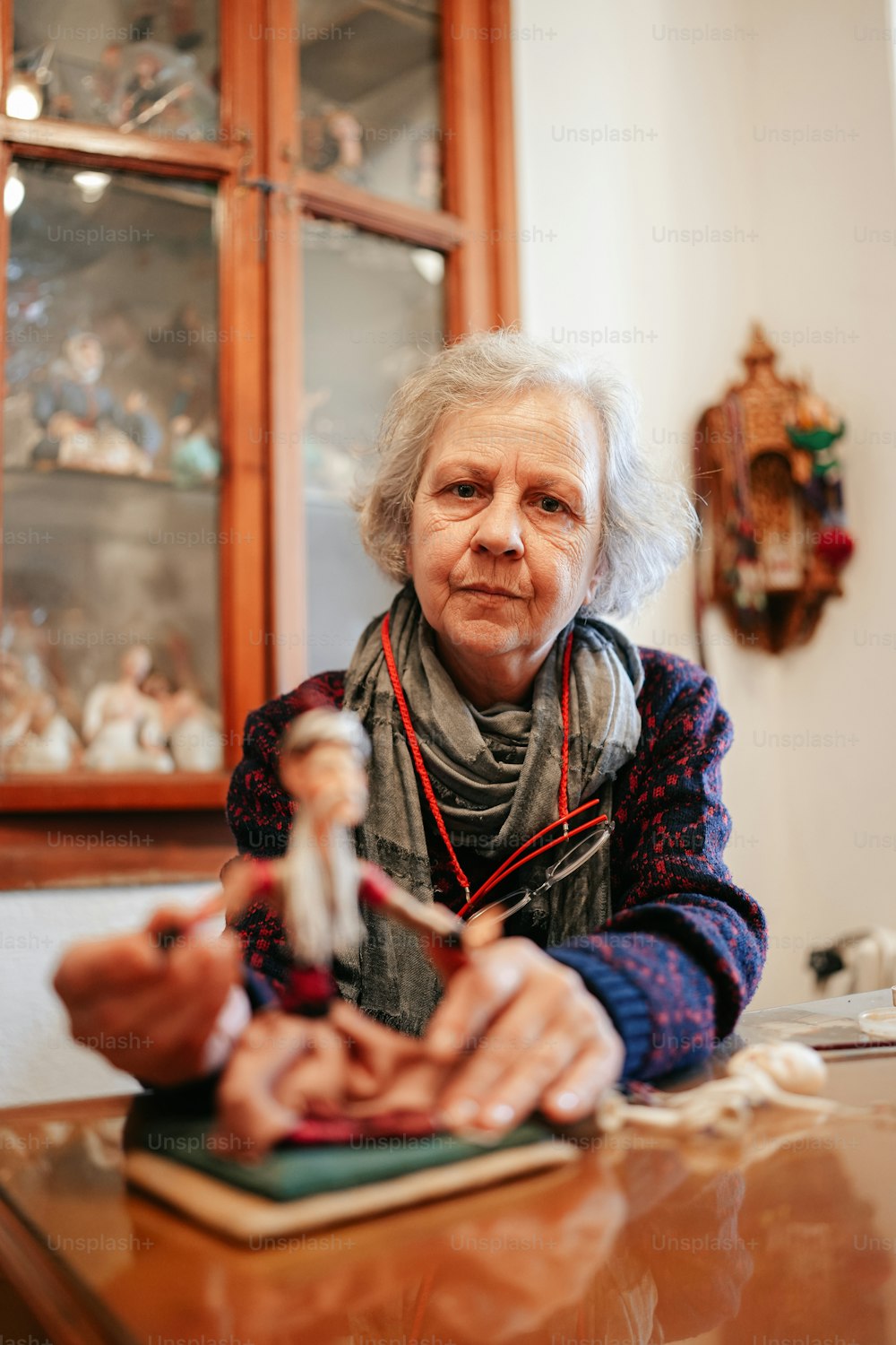 a woman sitting at a table with a doll in front of her