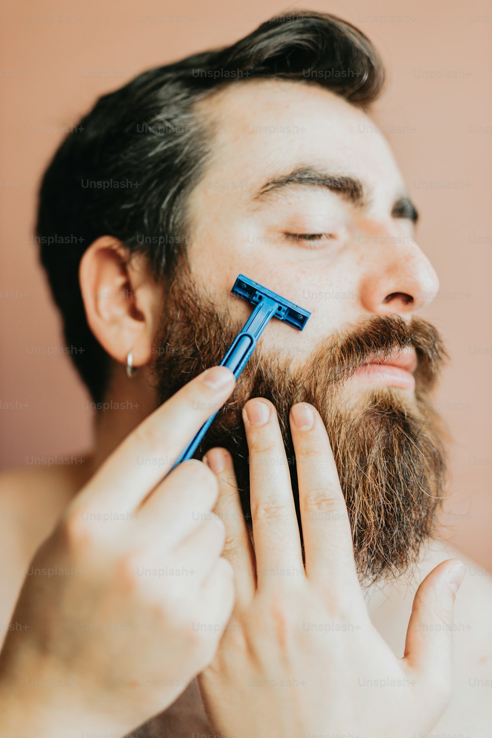 a man is shaving his beard with an electric razor