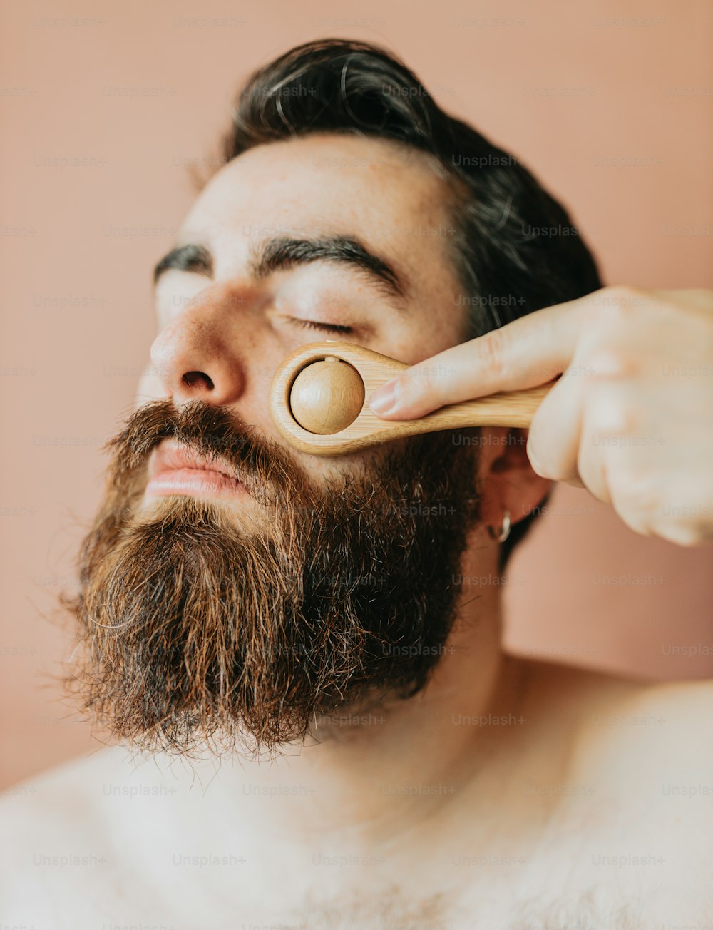 um homem está escovando a barba com uma escova de madeira