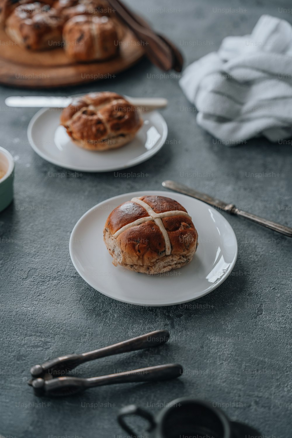 a hot cross bun on a plate next to a cup of coffee