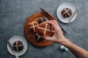 a person holding a hot cross bun on a plate