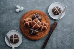 a wooden plate topped with hot cross buns