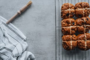 hot cross buns on a cooling rack with a rolling pin