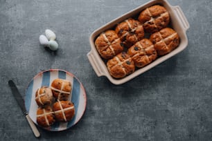 a plate of hot cross buns next to a bowl of eggs