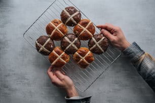 a person holding a wire rack with pastries on it