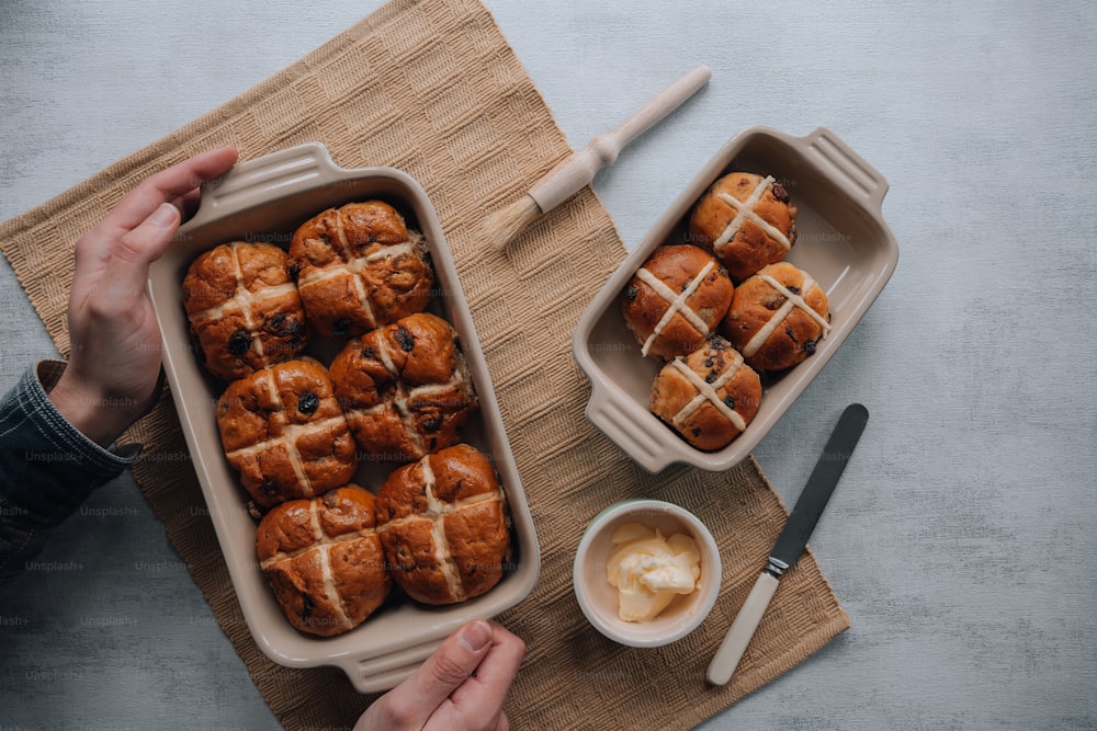 a person holding a tray of hot cross buns