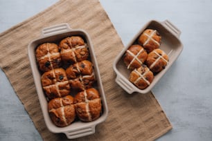 a tray of hot cross buns next to a container of hot cross buns