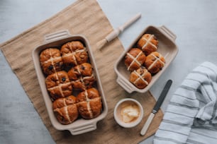 a tray of hot cross buns next to a bowl of dipping sauce